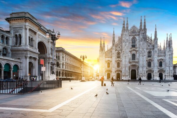 Elegant couple walking through Galleria Vittorio Emanuele II in Milan, dressed for the opera, with luxury boutiques and warm evening lights